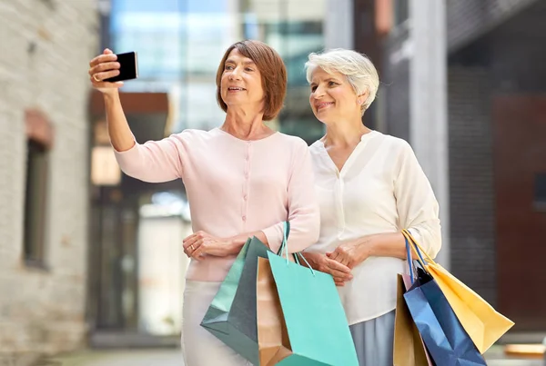 Şehirde selfie çeken alışveriş poşetleri ile yaşlı kadınlar — Stok fotoğraf