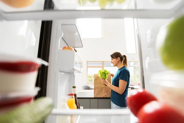 Vue à la femme avec la nourriture achetée du réfrigérateur à la maison — Photo