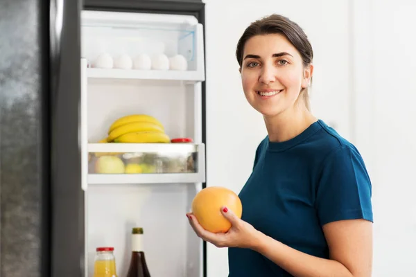 Щаслива жінка бере їжу з холодильника вдома — стокове фото
