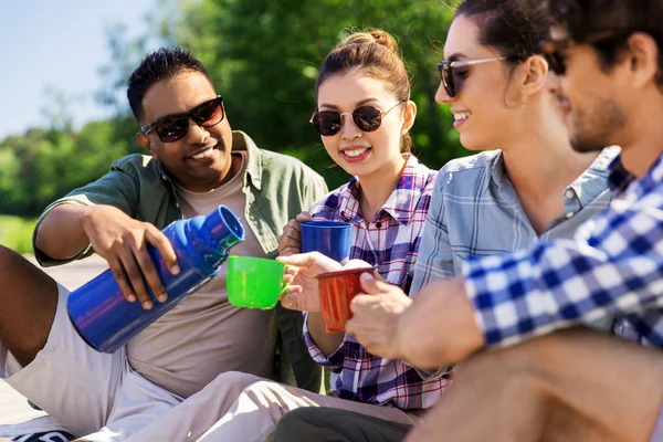 Amici felici bere il tè dal thermos in estate — Foto Stock