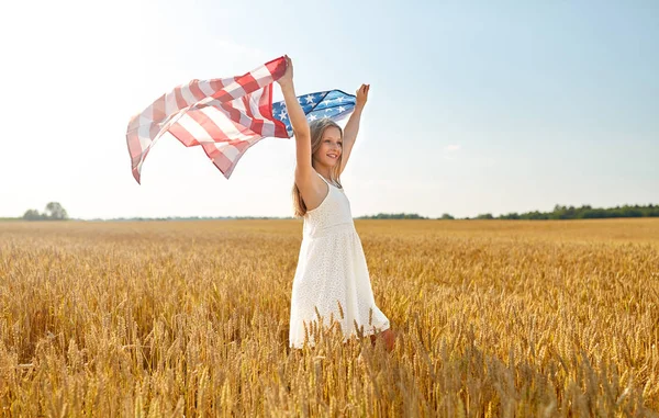 Дівчина з американським прапором махає над зерновим полем — стокове фото