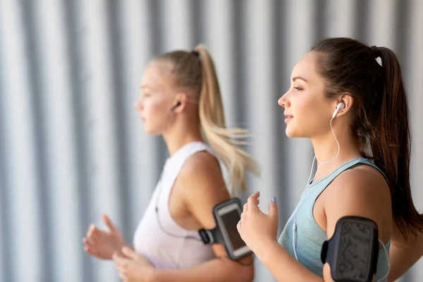 Mujeres jóvenes con auriculares y smartphones funcionando — Foto de Stock