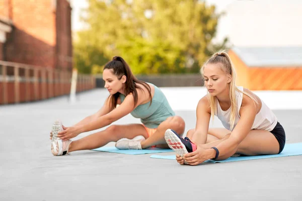 Mujeres con rastreadores de fitness que se extienden al aire libre —  Fotos de Stock