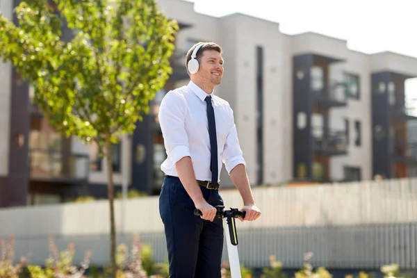 Hombre de negocios con auriculares scooter en la ciudad —  Fotos de Stock