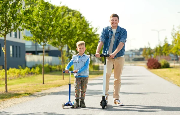 Padre e hijo pequeño montando scooters en la ciudad —  Fotos de Stock