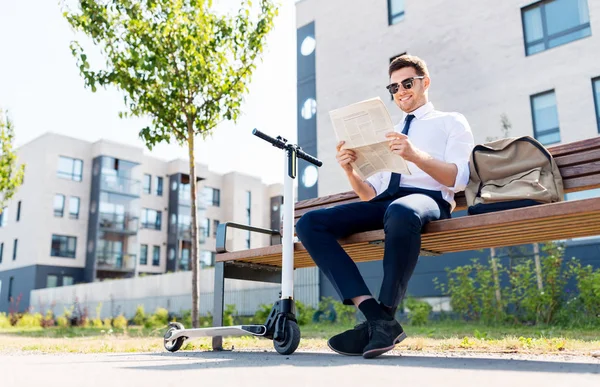 Бизнесмен со скутером читает газету в городе — стоковое фото