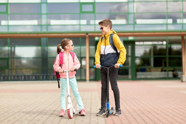 Bambini felici della scuola con zaini e scooter — Foto Stock