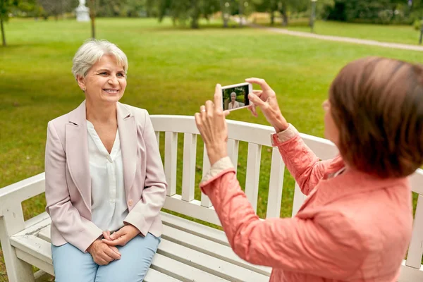 Старша жінка фотографує свого друга в парку — стокове фото