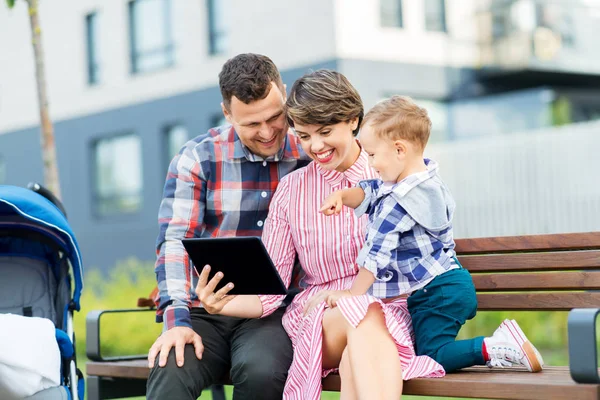 Rodina s počítačem Tablet PC sedícího na lavičce ve městě — Stock fotografie