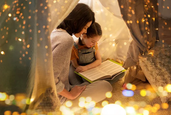 Libro de lectura familiar feliz en tienda de campaña para niños en casa —  Fotos de Stock