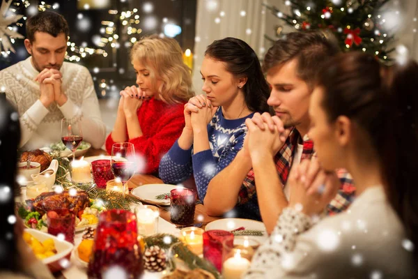 Friends having home christmas dinner and praying — Stock Photo, Image