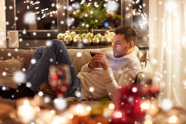 Man met smartphone thuis voor kerst — Stockfoto