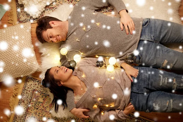 Glückliches Paar mit Girlande zu Hause auf dem Boden liegend — Stockfoto