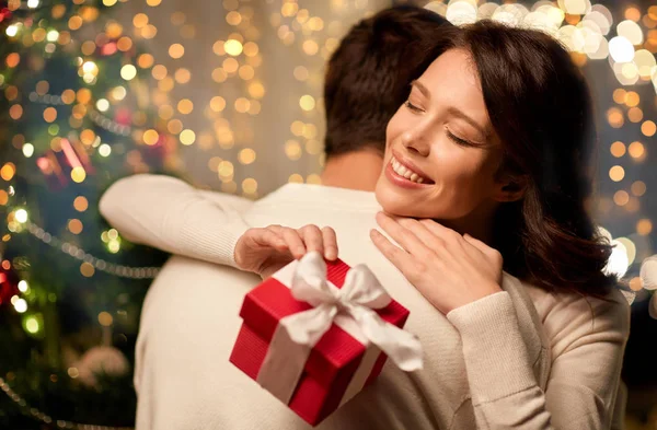 Szczęśliwy para z Boże Narodzenie prezent przytulanie w domu — Zdjęcie stockowe
