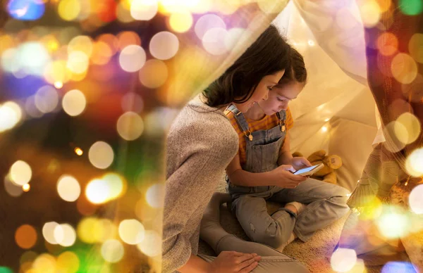 Щаслива сім'я зі смартфоном у дитячому наметі вдома — стокове фото
