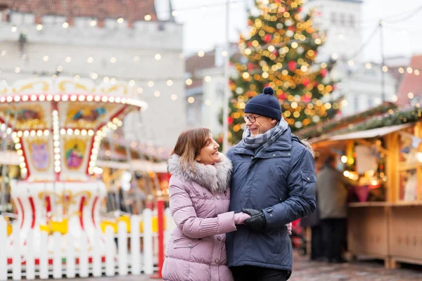 Щаслива старша пара обіймається на різдвяному ринку — стокове фото