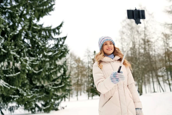 Женщина фотографирует селфи-палкой зимой — стоковое фото
