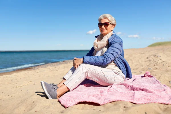 Heureuse femme âgée en veste sur la plage — Photo