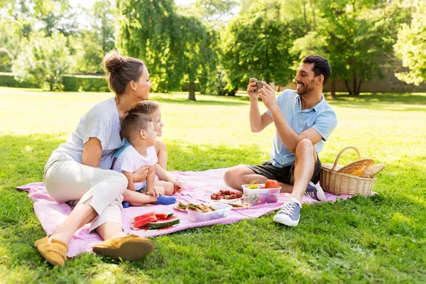 Padre che fotografa la famiglia al picnic al parco — Foto Stock