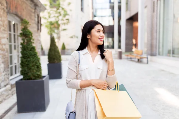 Asiatin mit Einkaufstüten läuft durch die Stadt — Stockfoto