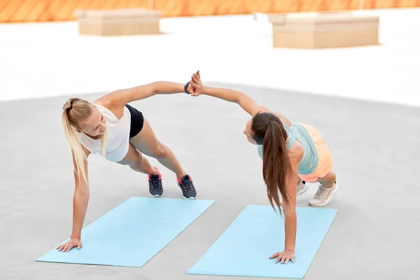 Mujeres haciendo alto cinco en tablón lateral en alfombras deportivas —  Fotos de Stock