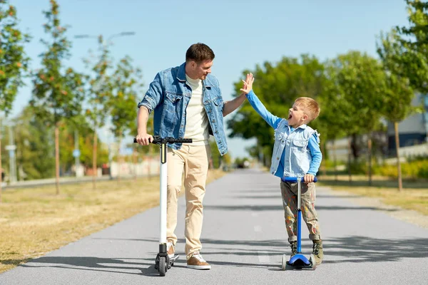 Vader en zoon met scooters maken high five — Stockfoto
