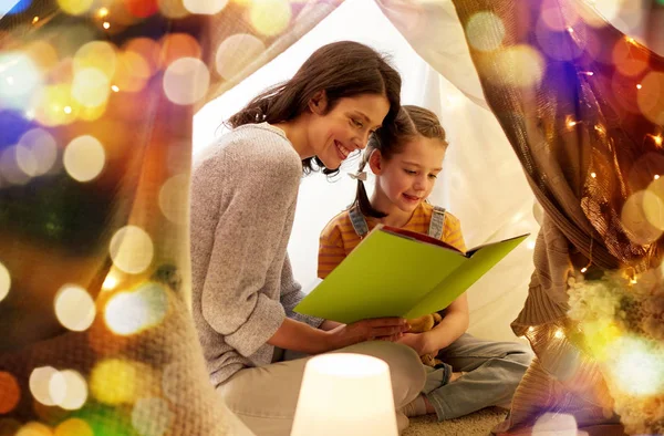 Libro de lectura familiar feliz en tienda de campaña para niños en casa — Foto de Stock