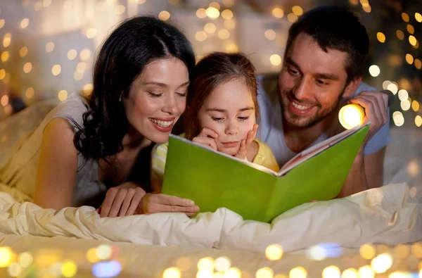 Libro de lectura familiar feliz en la cama por la noche en casa —  Fotos de Stock