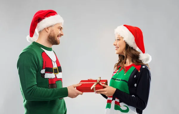 Casal feliz em camisolas de Natal com caixa de presente — Fotografia de Stock