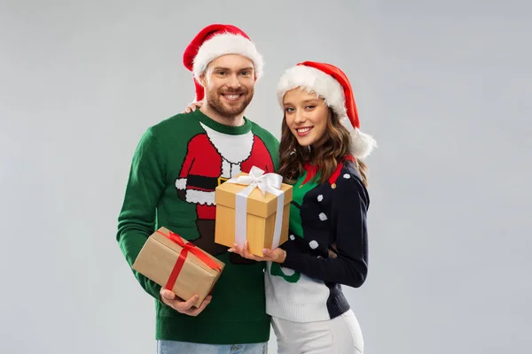 Casal feliz em camisolas de Natal com presentes — Fotografia de Stock