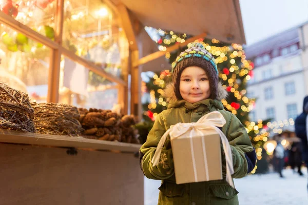 Niño feliz con caja de regalo en el mercado de Navidad — Foto de Stock