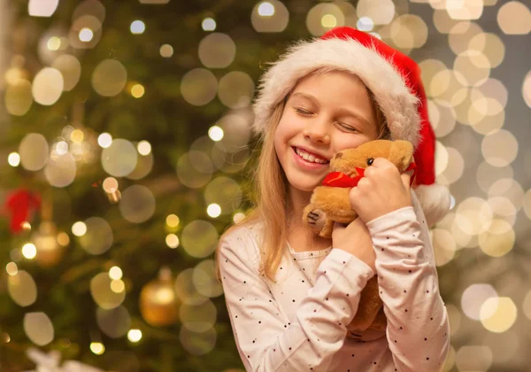 Smiling girl in santa hat with christmas gift — Stock Photo, Image