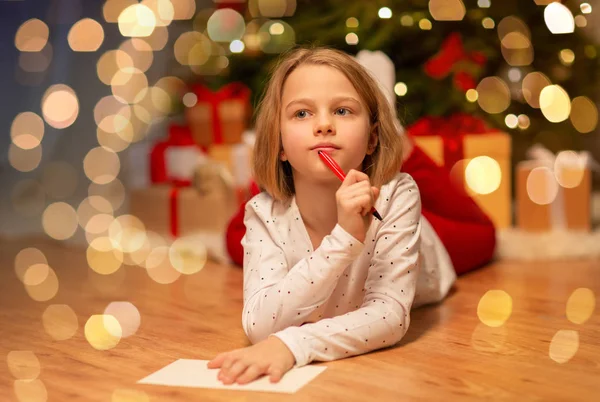 Chica escribiendo la lista de deseos de Navidad en casa —  Fotos de Stock