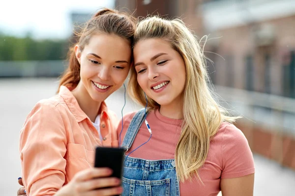 Teenage girls listening to music on smartphone — Stock Photo, Image