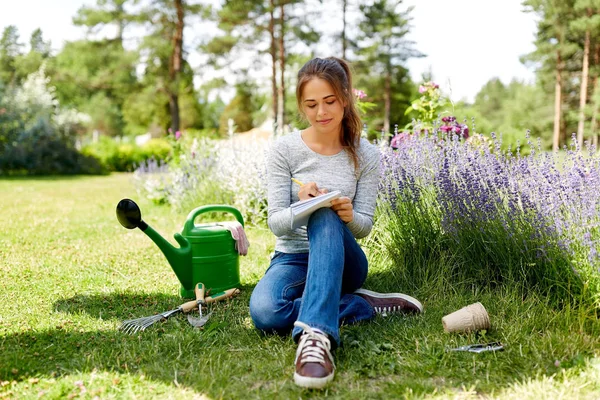 Yaz bahçesinde deftere yazan genç bir kadın. — Stok fotoğraf