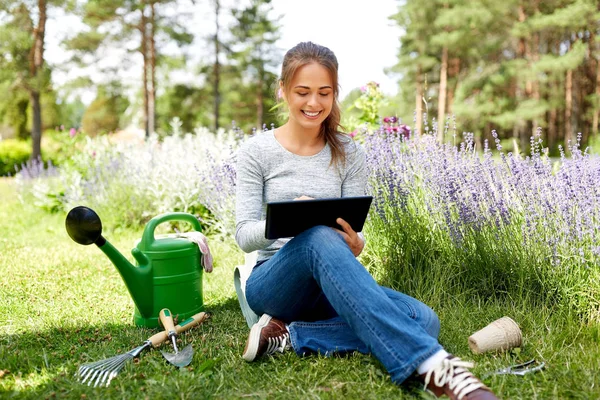 Mulher com tablet pc e ferramentas de jardim no verão — Fotografia de Stock