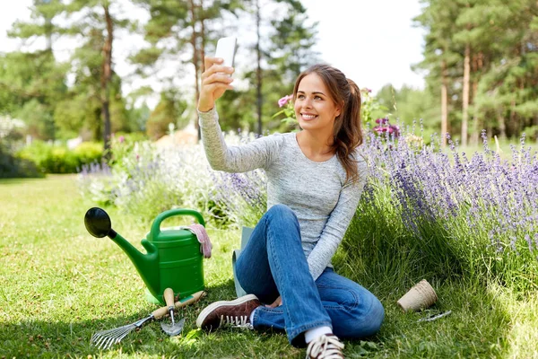Жінка бере селфі за допомогою смартфона в літньому саду — стокове фото