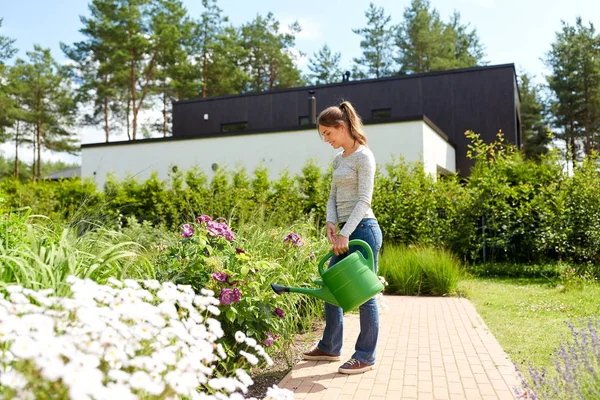 Jovem mulher regando flores no jardim — Fotografia de Stock
