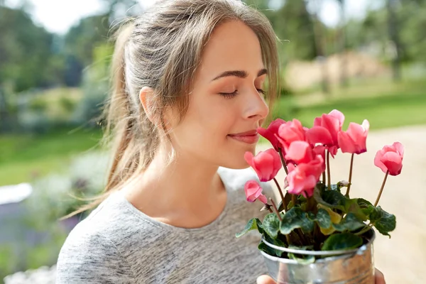 Mujer joven con flores de ciclamen en el jardín de verano —  Fotos de Stock