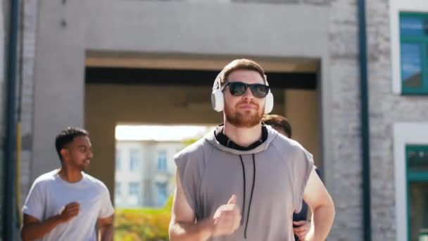 Amigos masculinos com fones de ouvido correndo ao ar livre — Vídeo de Stock