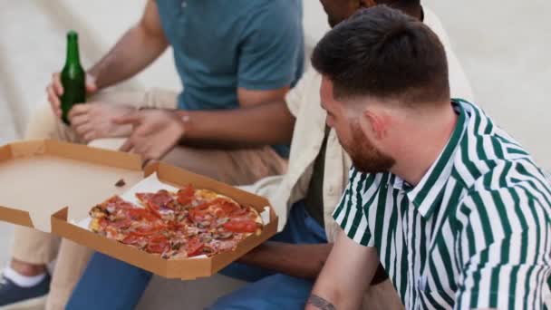 Amigos varones comiendo pizza con cerveza en la azotea — Vídeo de stock