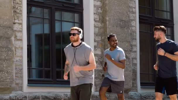 Amigos masculinos com fones de ouvido correndo ao ar livre — Vídeo de Stock