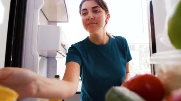 Frau erstellt Liste von Lebensmitteln auf Smartphone am Kühlschrank — Stockvideo