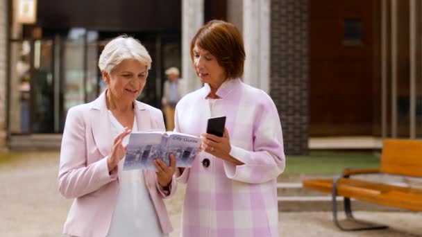 Senior women with city guide and smartphone — Stock Video
