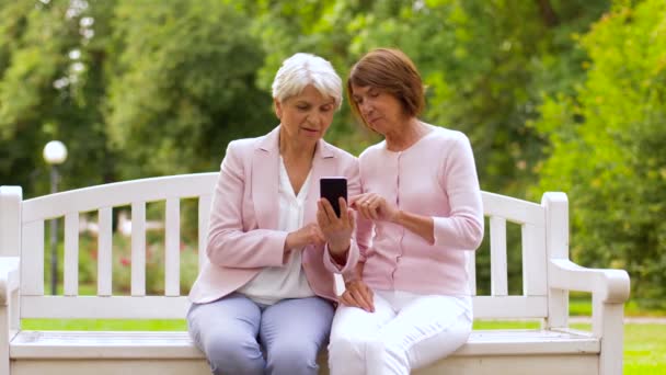 Glada äldre kvinnor med smartphone i sommarparken — Stockvideo