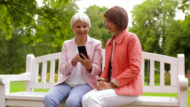 Счастливые пожилые женщины со смартфоном в летнем парке — стоковое видео