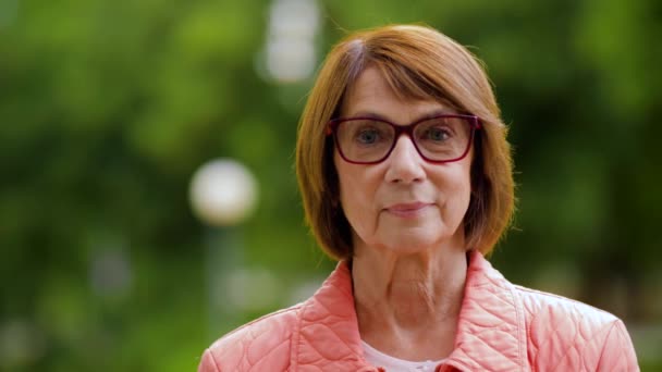 Портрет счастливой пожилой женщины в очках в парке — стоковое видео