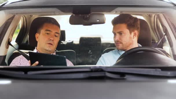 Мужчина с инструктором по вождению разговаривает в машине — стоковое видео