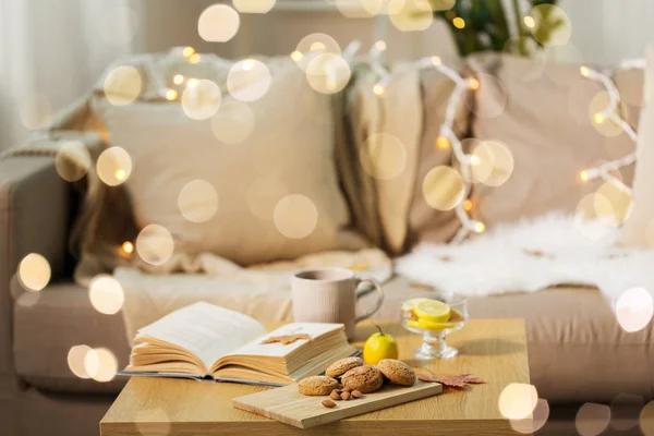 Galletas de avena, libro, té y limón en la mesa en casa — Foto de Stock