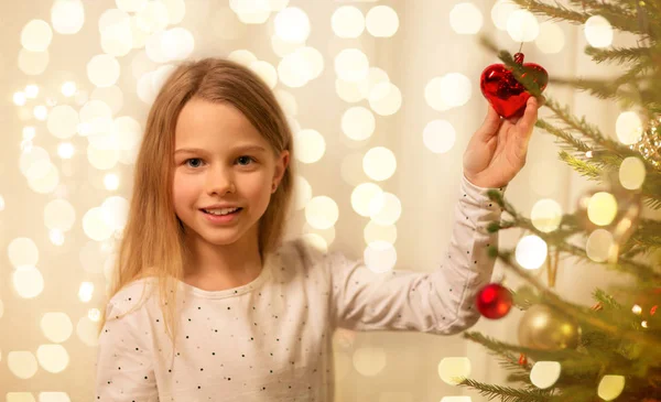 Happy girl in red dress decorating christmas tree — Stock Photo, Image